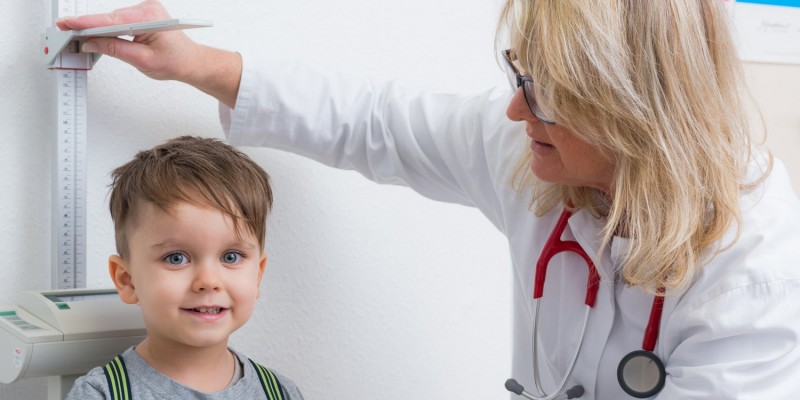 Junge wird beim Kinderarzt vermessen